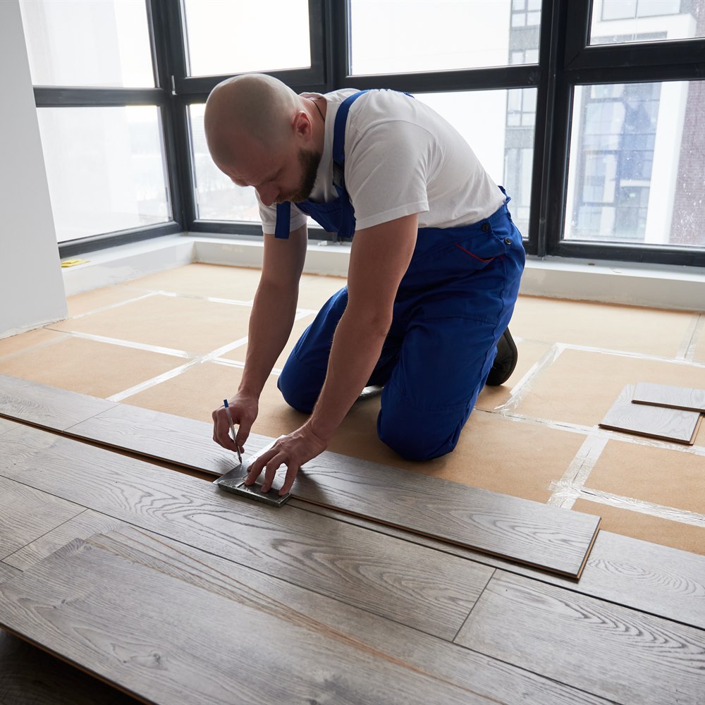 Man installing wood flooring in new apartment