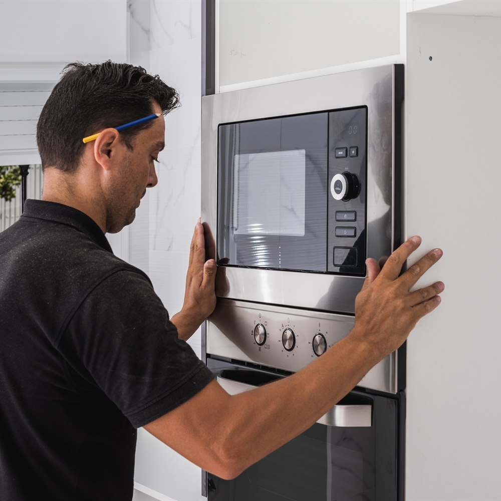 Man installs stainless steel oven in kitchen