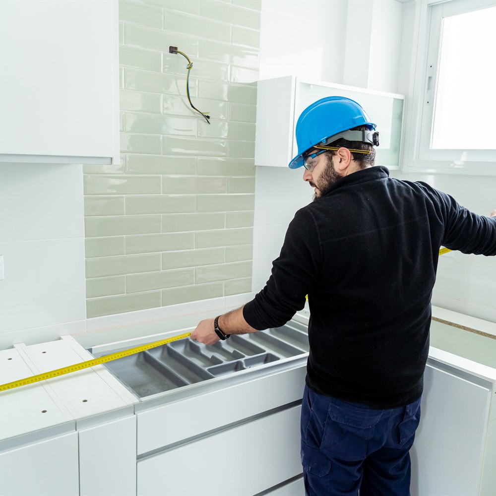 Man measures kitchen cabinet with tape measures