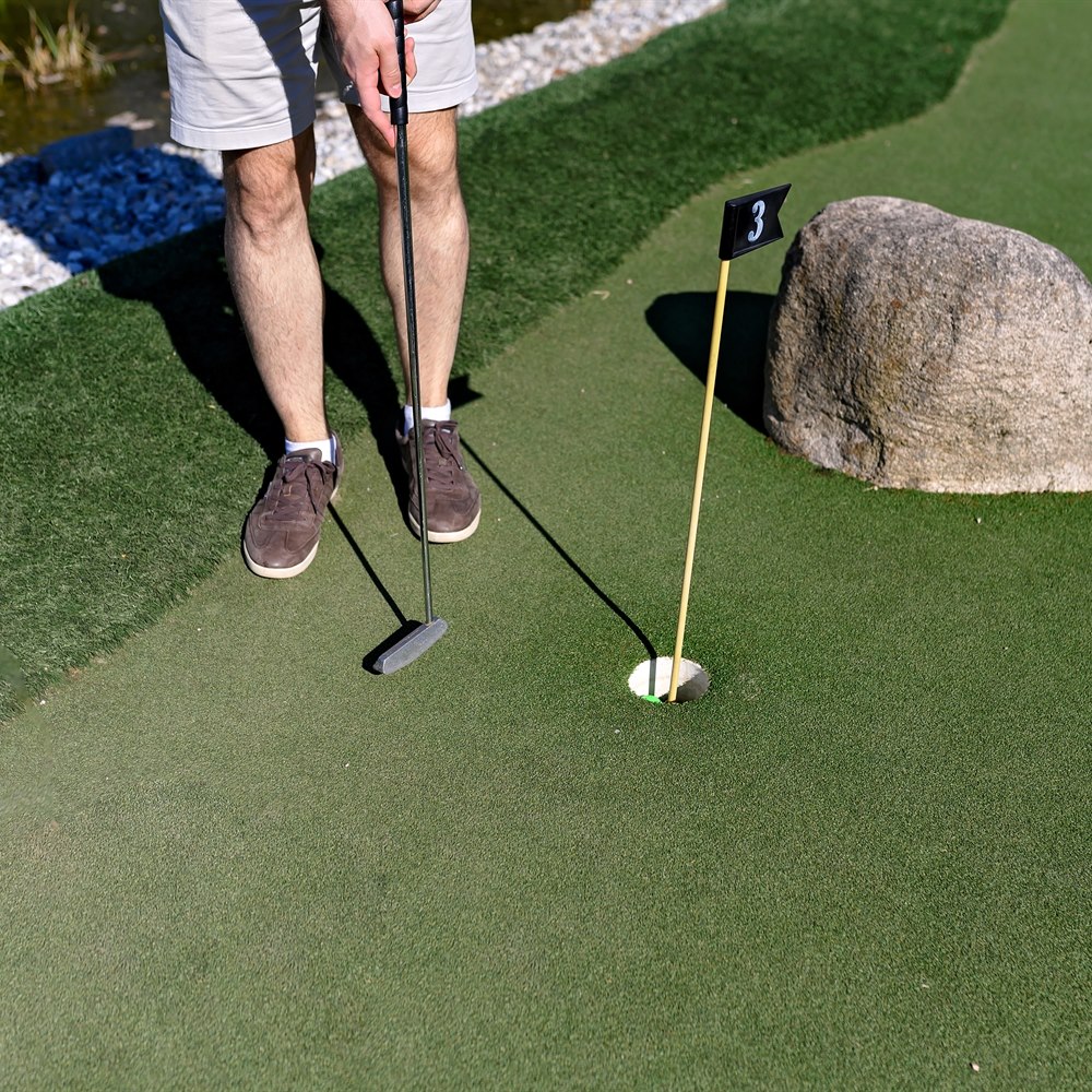 man-plays-mini-golf-outdoors-on-sunny-day Man plays mini golf outdoors on sunny day