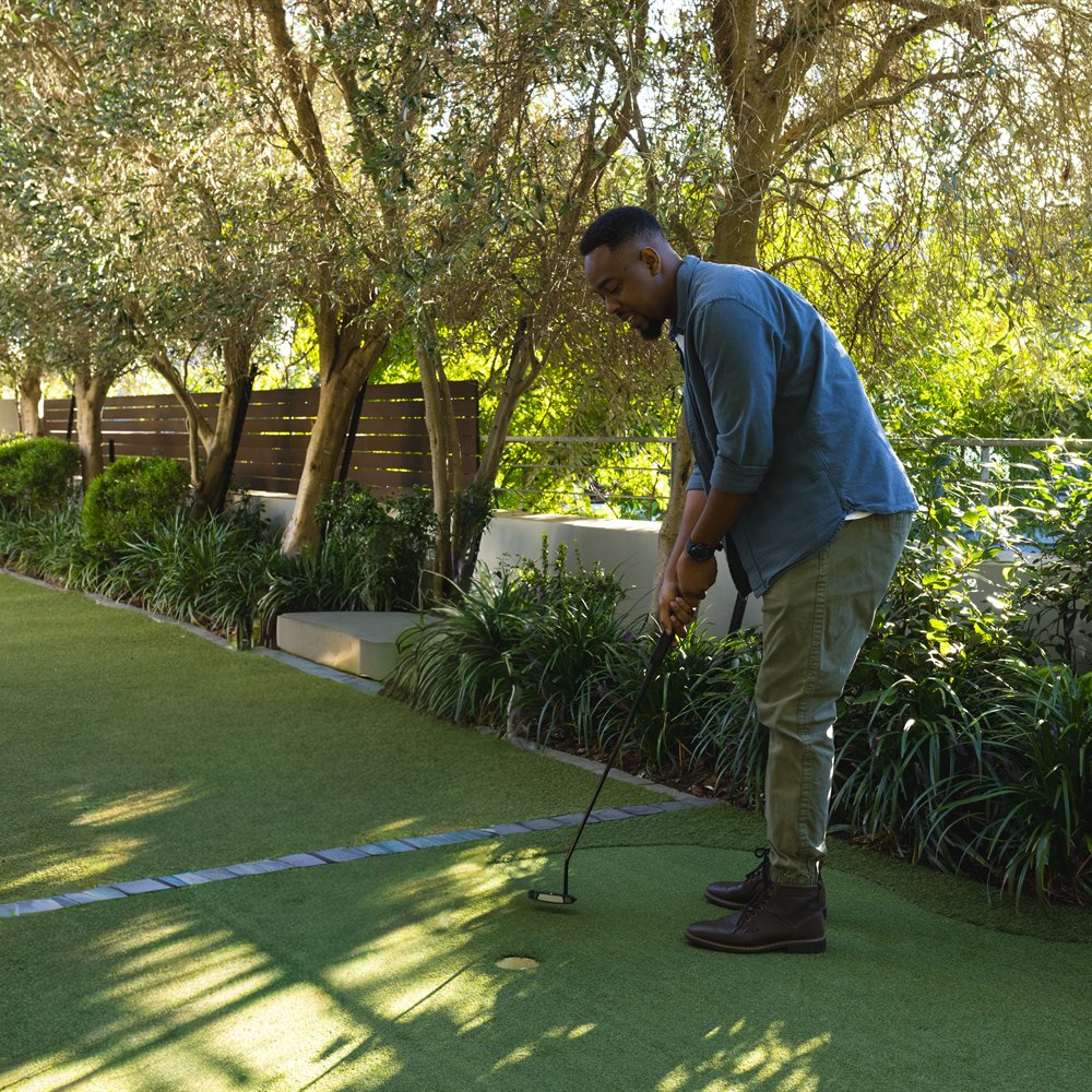 Man practicing golf putting on a backyard green