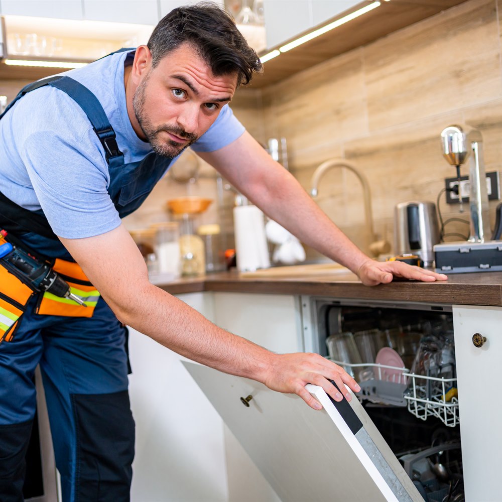 Man repairing dishwasher in contemporary kitchen