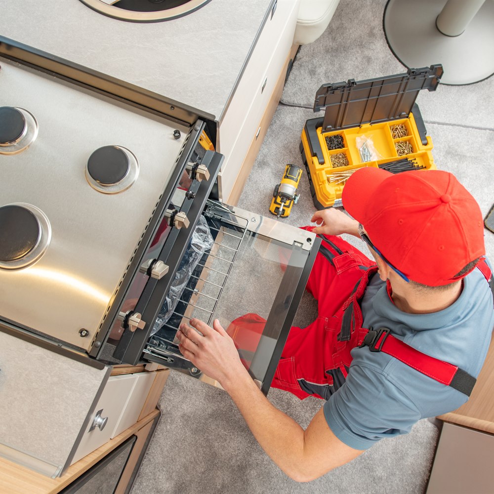 Man repairing gas stove in rv kitchen