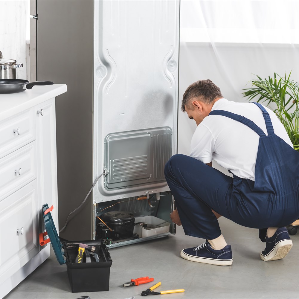 Man repairing refrigerator in a modern kitchen