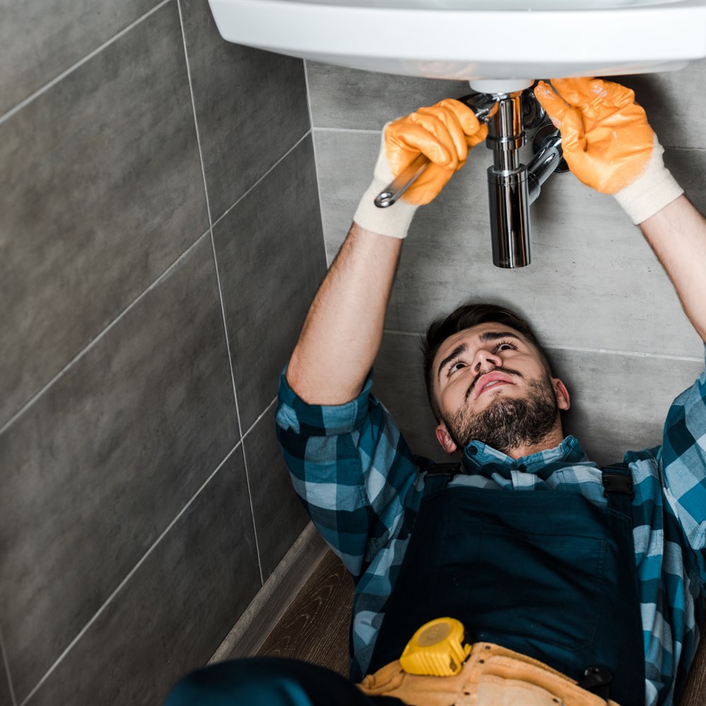 Man repairing sink in bathroom wearing gloves