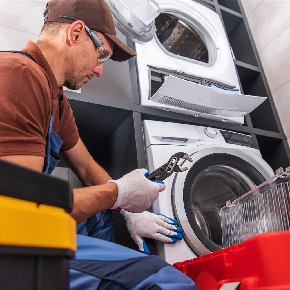 Man repairs washing machine with adjustable wrench