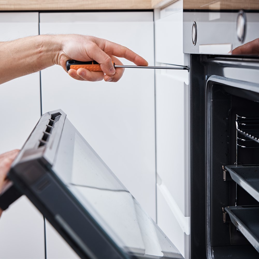 Oven repair by adult with screwdriver in kitchen