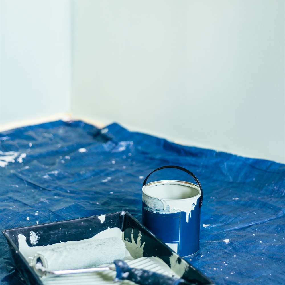 Paint can roller and tray on blue tarp