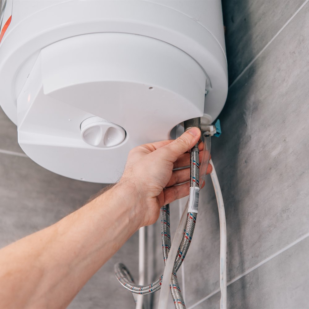 Plumber connecting braided hose to hot water tank