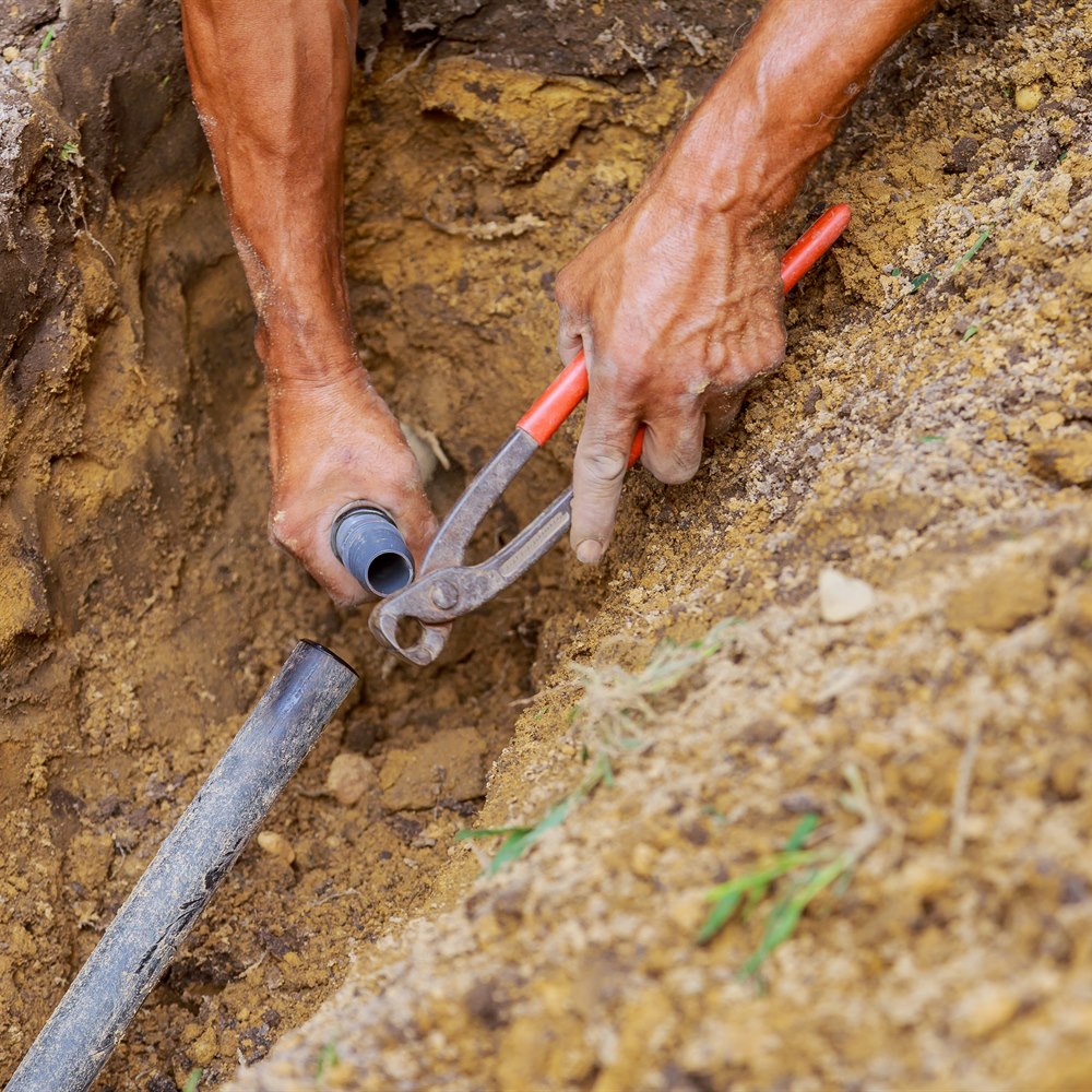 Plumber fitting pipe in a trench outdoors