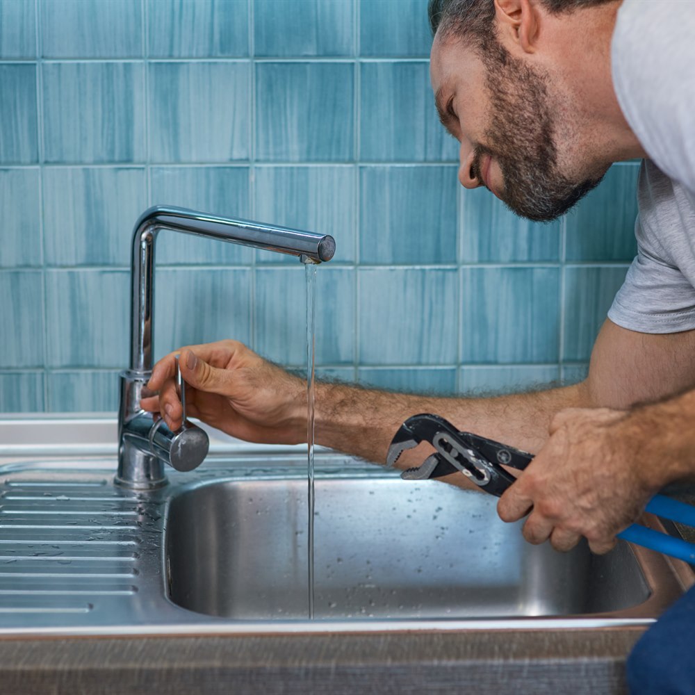 Plumber fixing a sink in a home kitchen