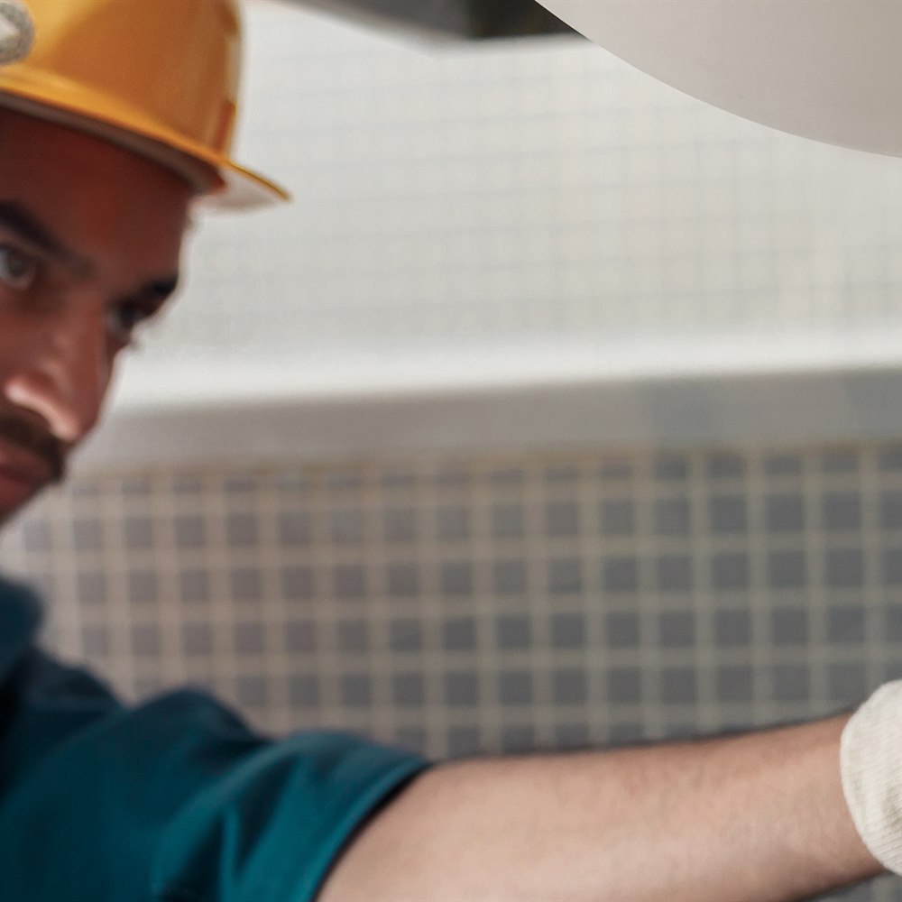 Plumber fixing sink pipe in bright bathroom