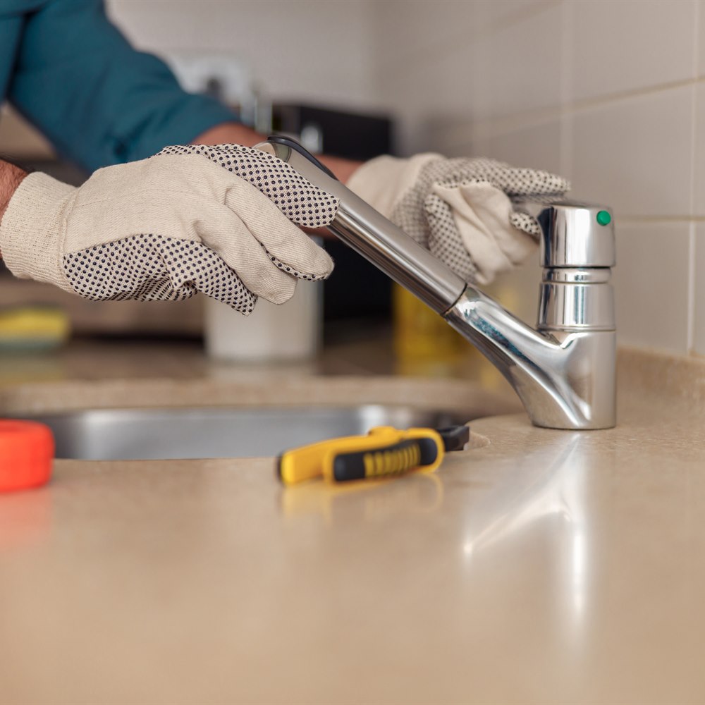 Plumber repairing a faucet in a kitchen sink