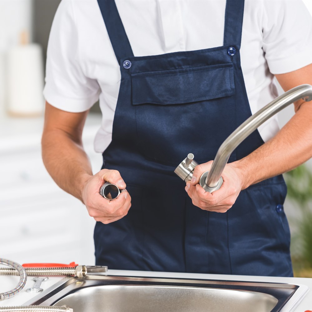 Plumber repairing sink in kitchen during daytime