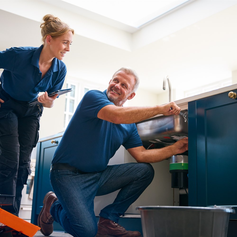 Plumber team working on sink repair in kitchen