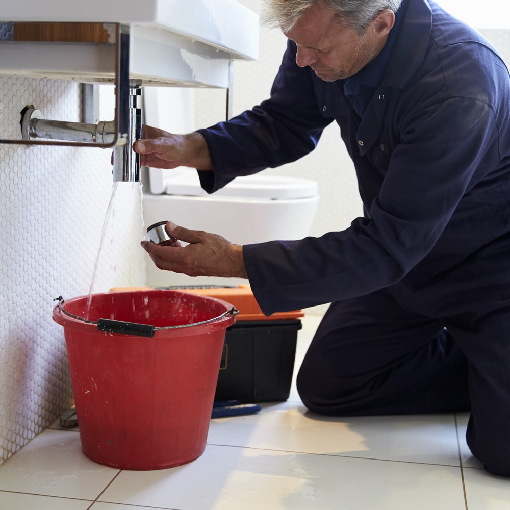 Plumber working on sink drain in bathroom