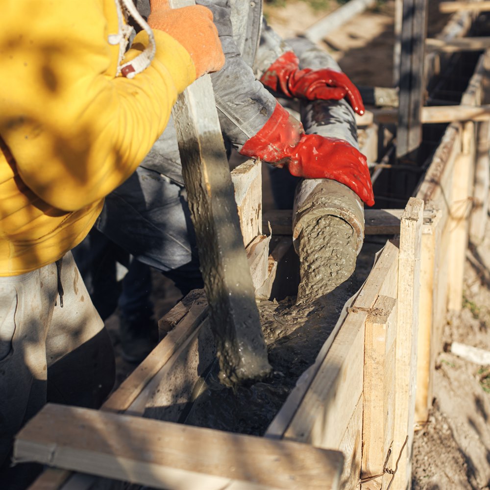 Pouring concrete into wooden form on construction