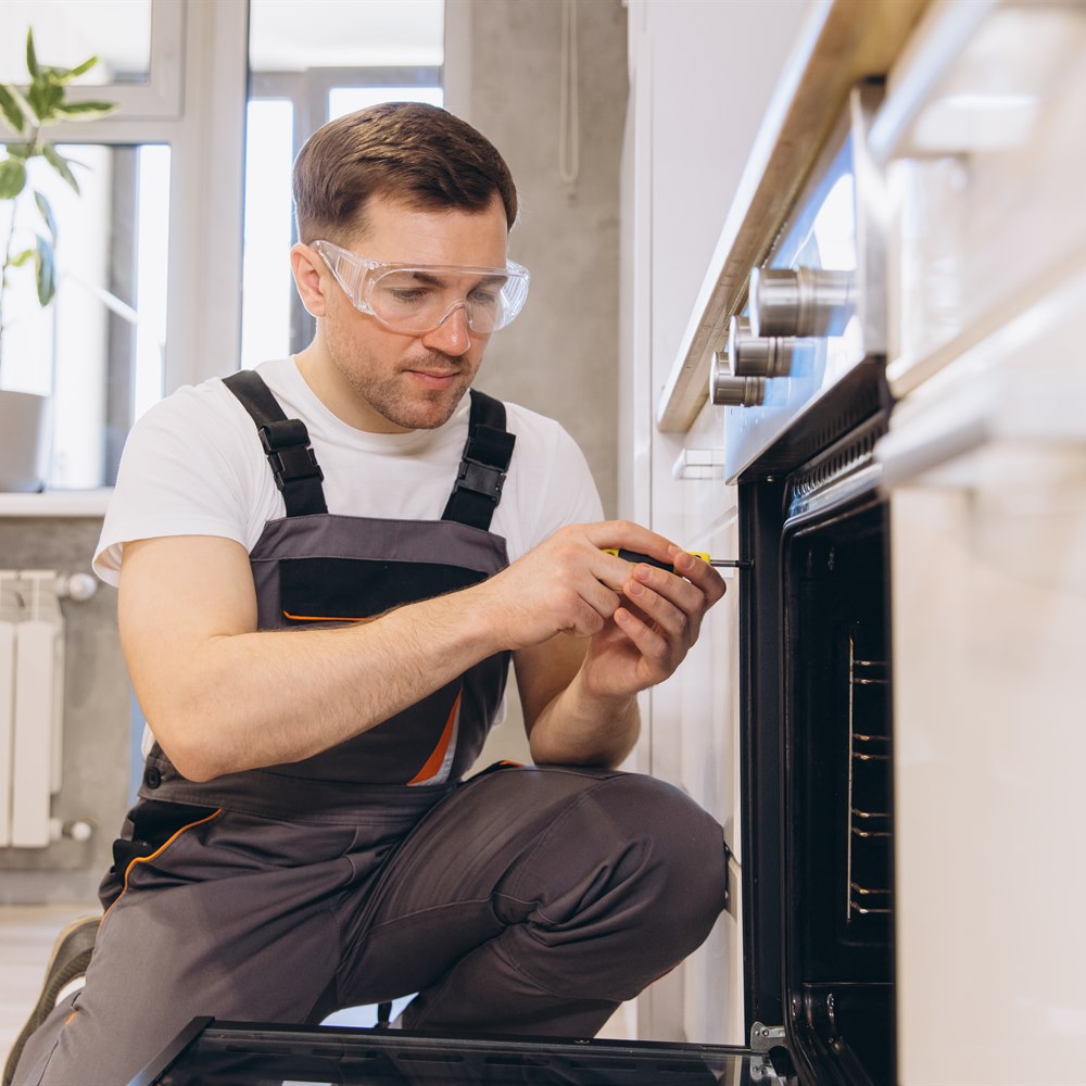 Professional plumber repairing oven in a kitchen