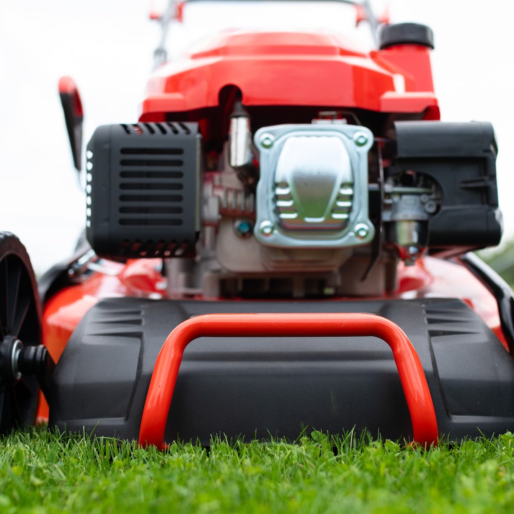 red-lawnmower-on-green-grass-in-rural-setting Red lawnmower on green grass in rural setting