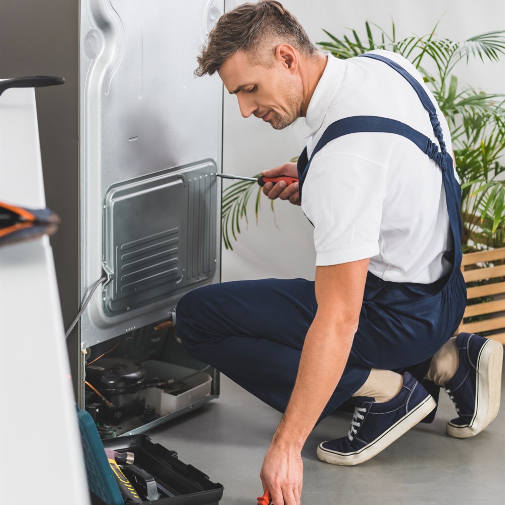 Refrigerator repair with a man in overalls