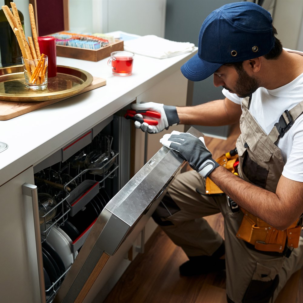 repair-technician-fixing-dishwasher-appliance Repair technician fixing dishwasher appliance