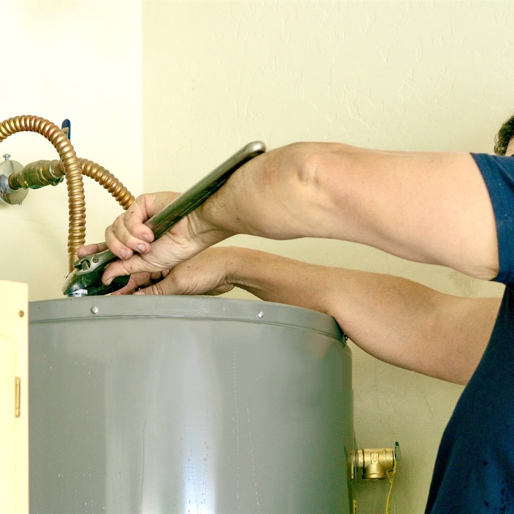 repairing-the-water-heater-with-wrench-indoors Repairing the water heater with wrench indoors