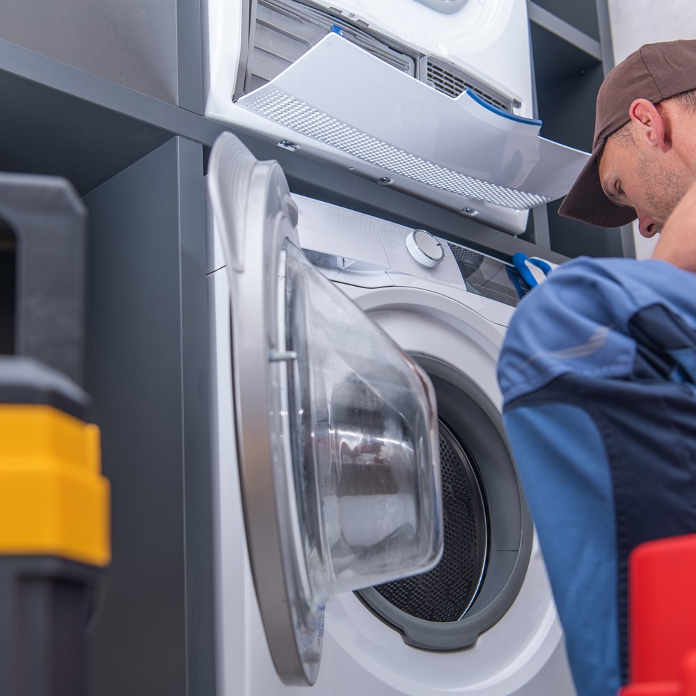 Repairman fixing appliance inside residential laundry