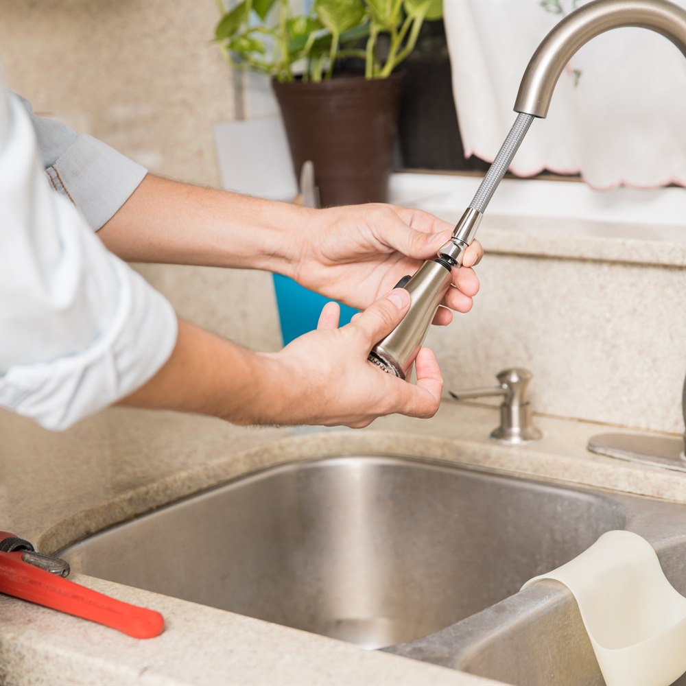 Repairman fixing the kitchen faucet at home