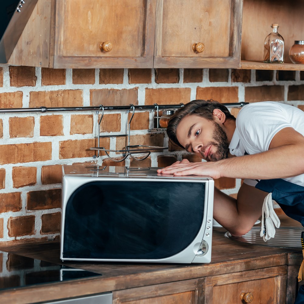 Repairman inspecting kitchen microwave at home