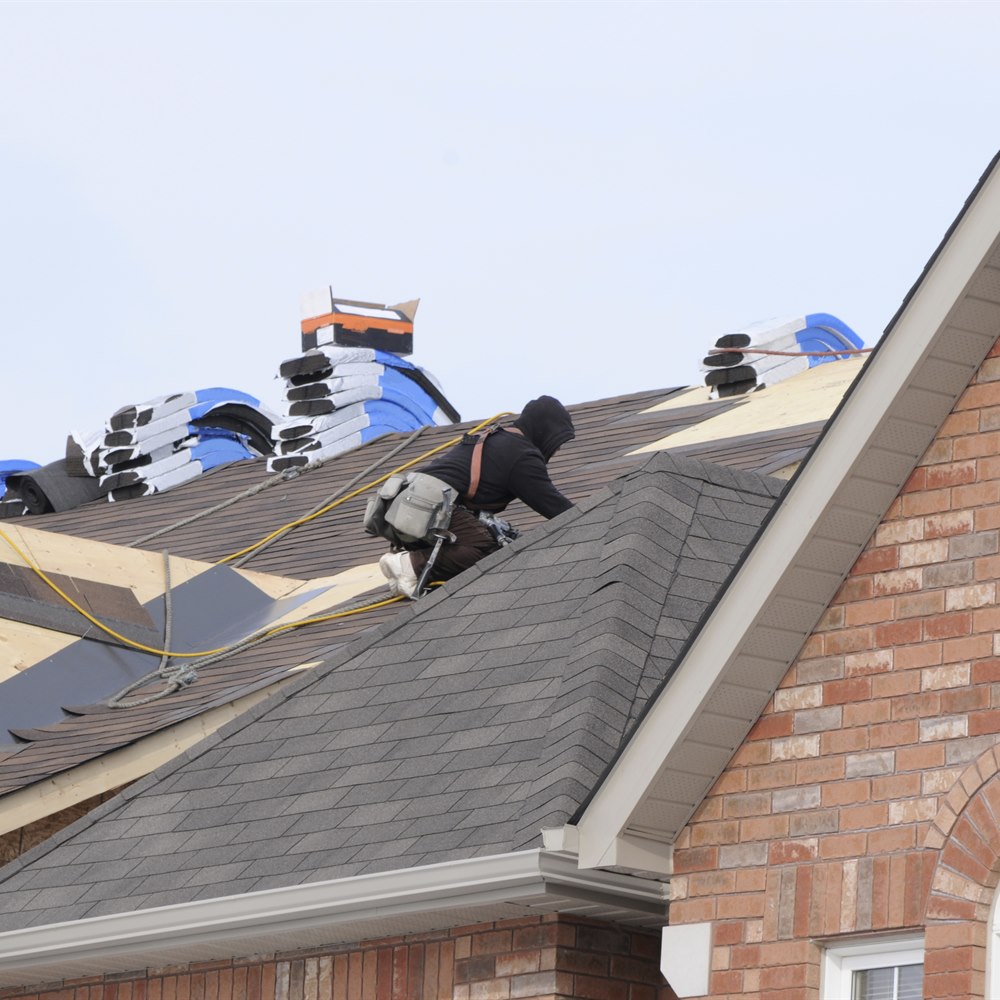 Roofer on new home with shingle bundles
