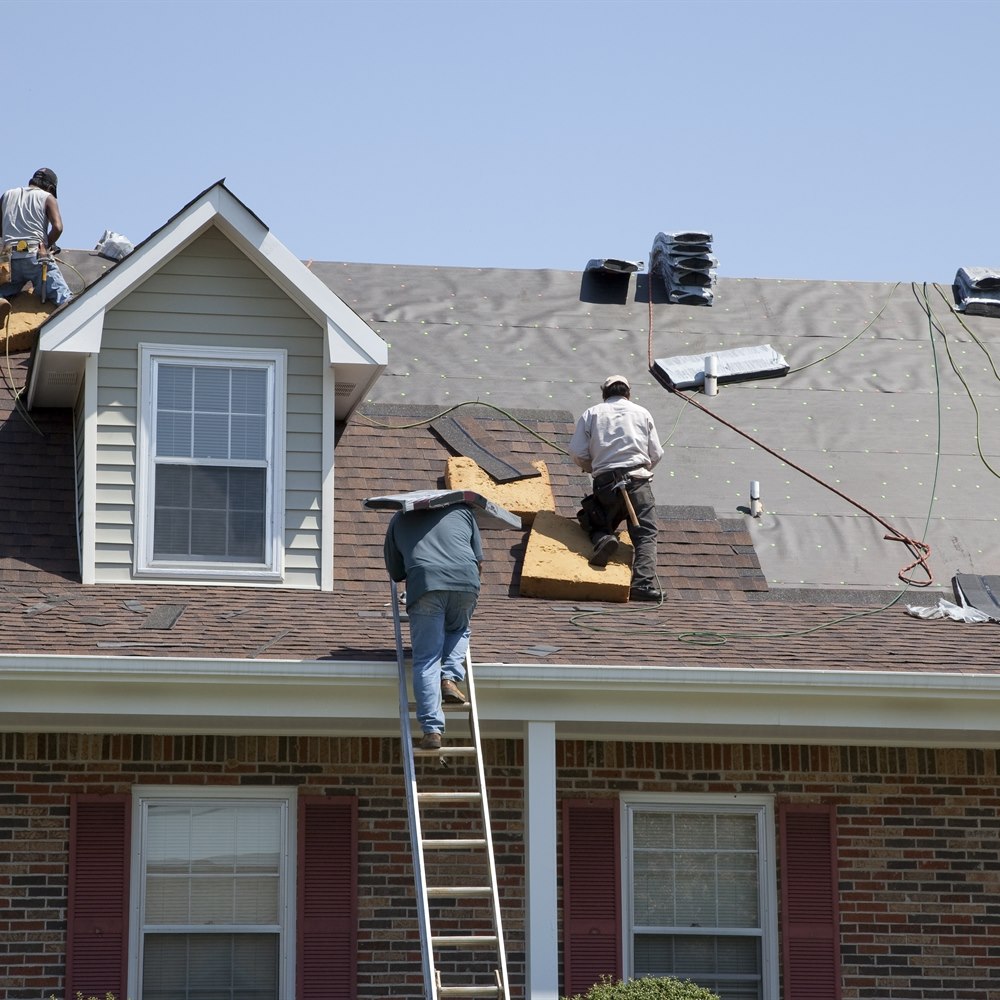 Roofers replacing shingles on house roof