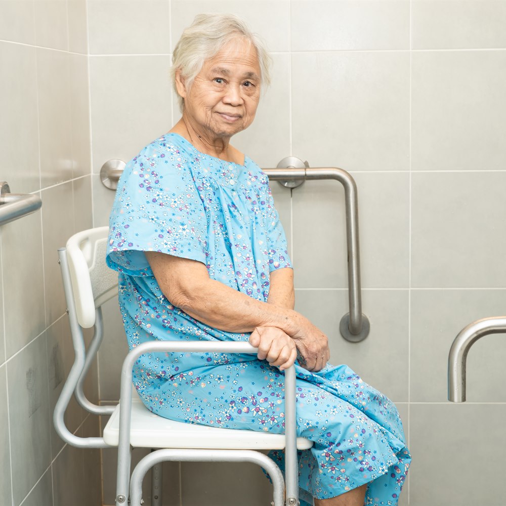 Senior woman sitting in bathroom with assistance