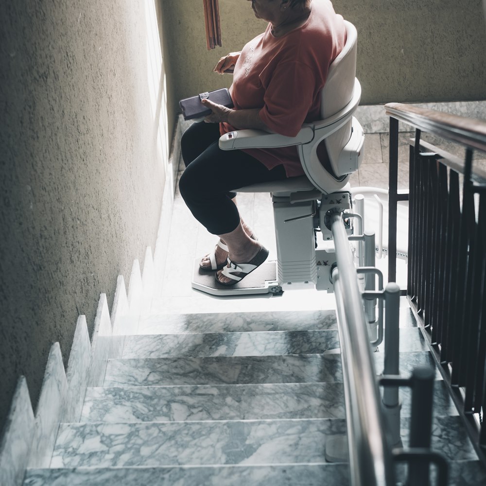 Senior woman using stair lift in home