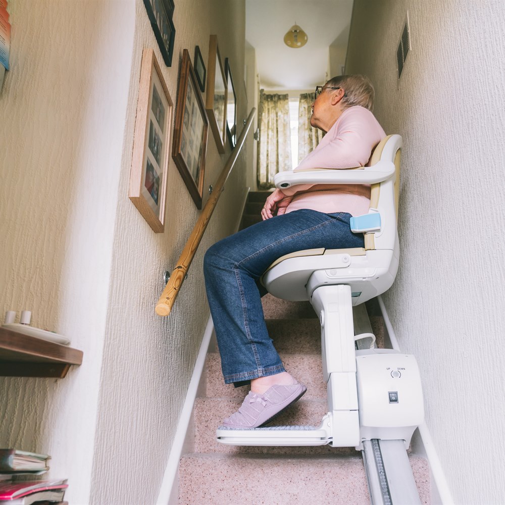 Senior woman using stairlift in bright home