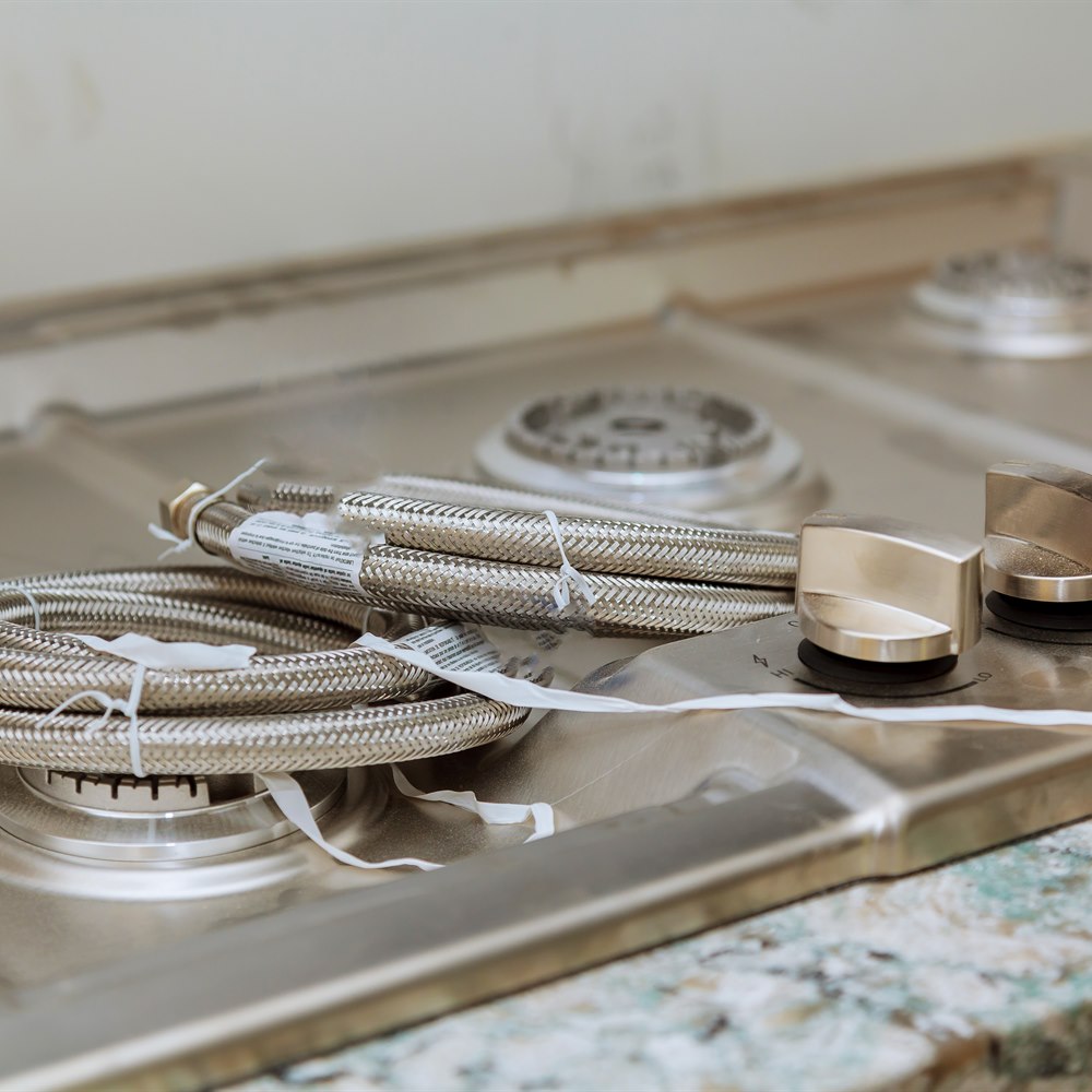 Shiny braided hose on a stove top