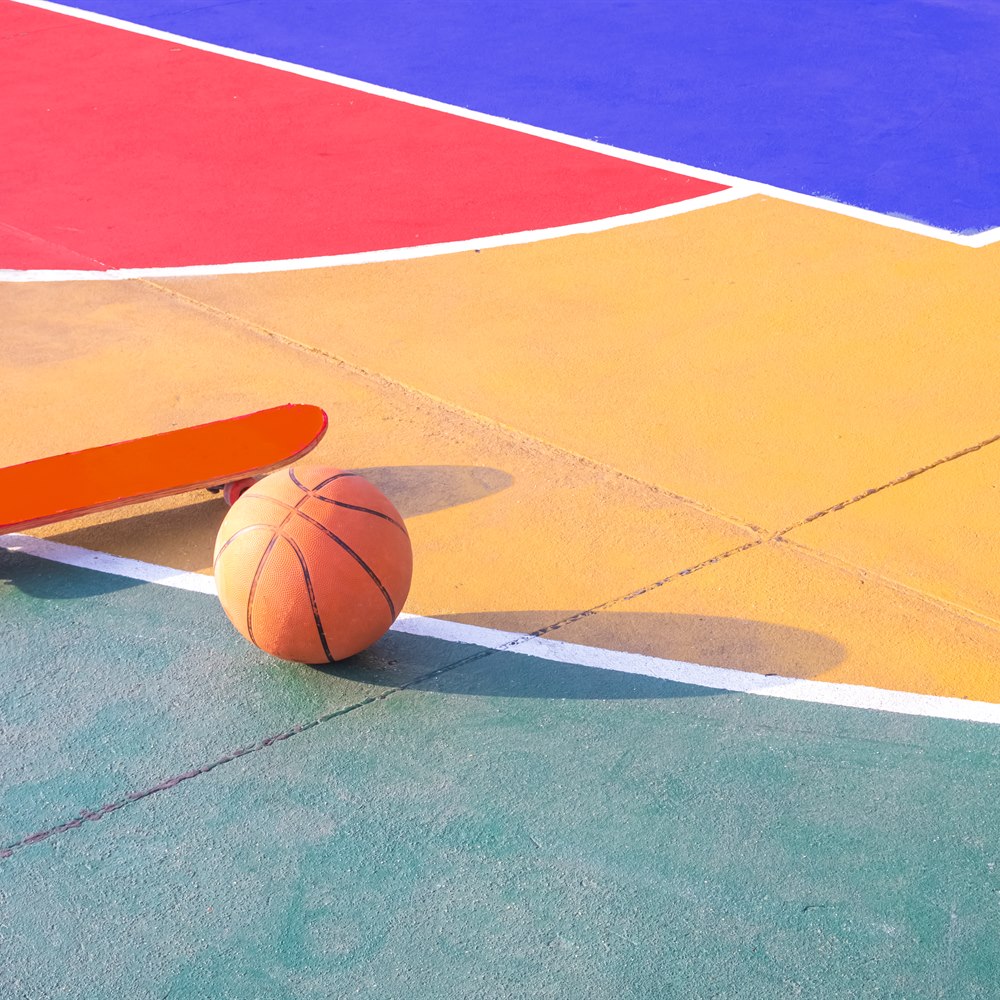 Skateboard and basketball on a multicolored court