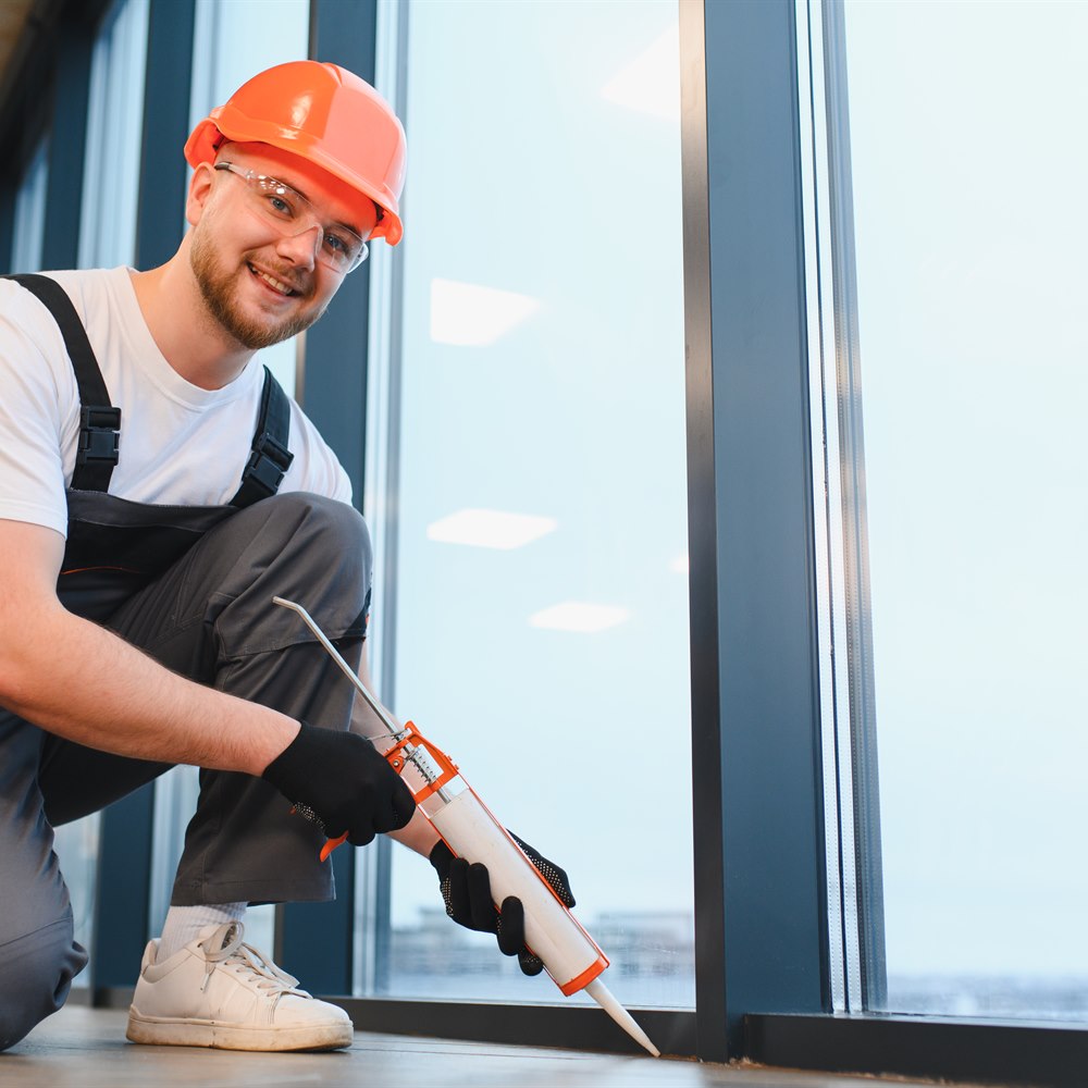 Smiling construction worker using caulking gun