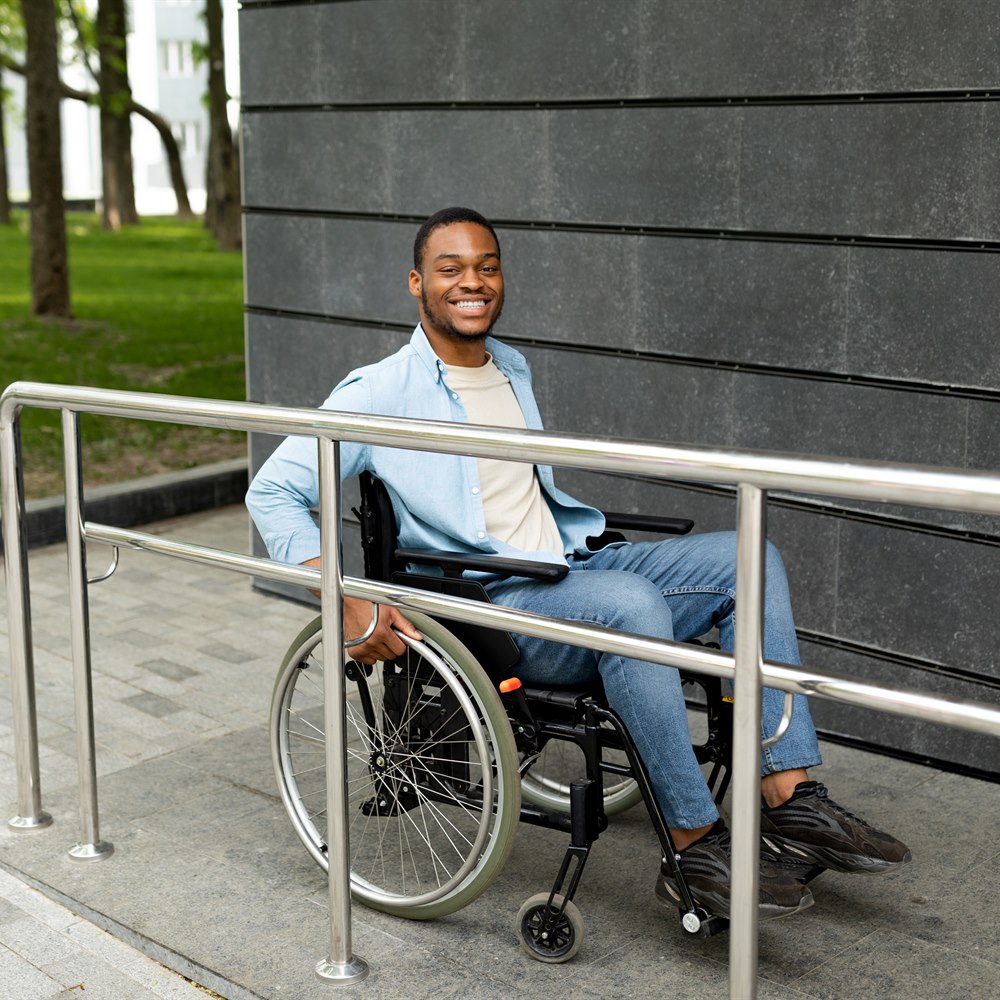 Smiling man in wheelchair on city sidewalk