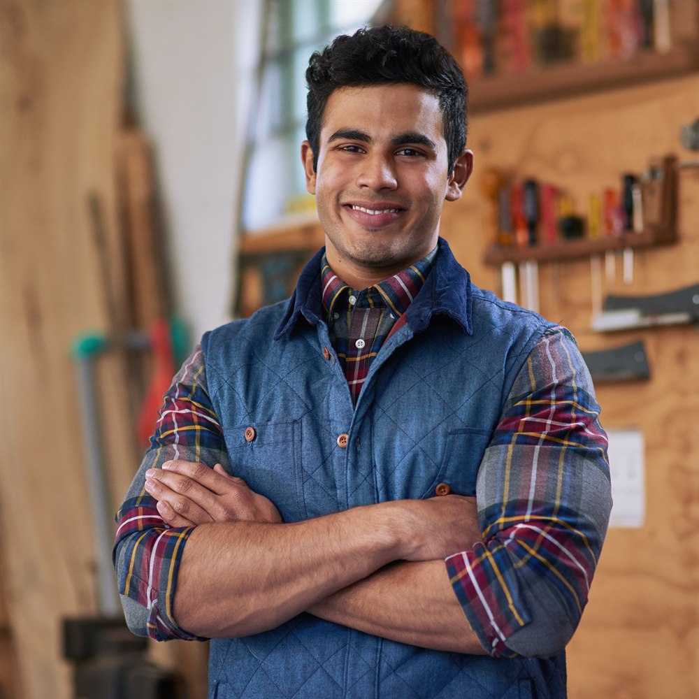 Smiling man in workshop with arms crossed