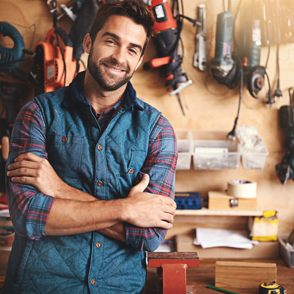 smiling-man-standing-in-his-workshop Smiling man standing in his workshop
