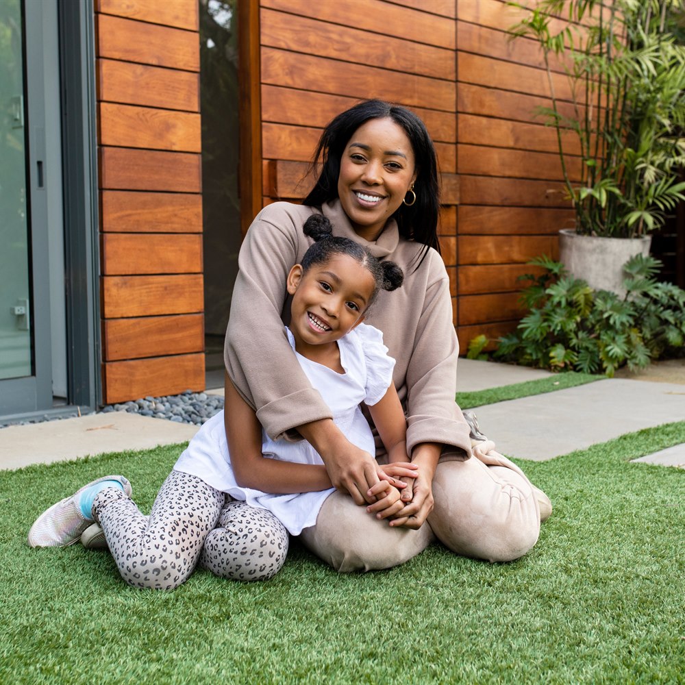 Smiling woman and child posing in yard
