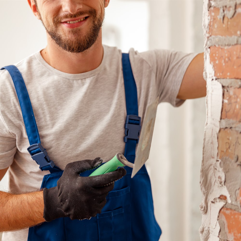 smiling-worker-tiling-a-wall-with-trowel Smiling worker tiling a wall with trowel
