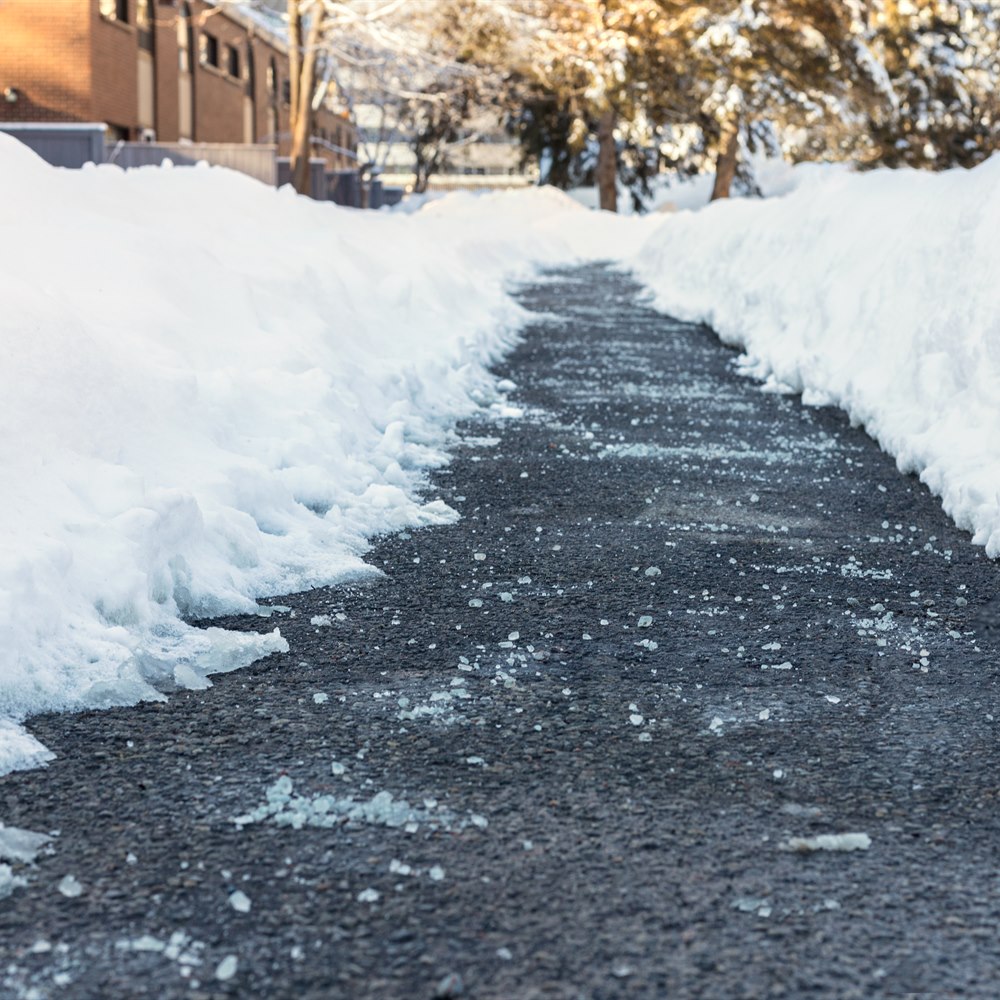 Snowy sidewalk path through winter city street