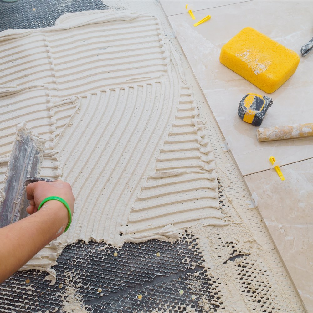 Spreading tile adhesive with notched trowel