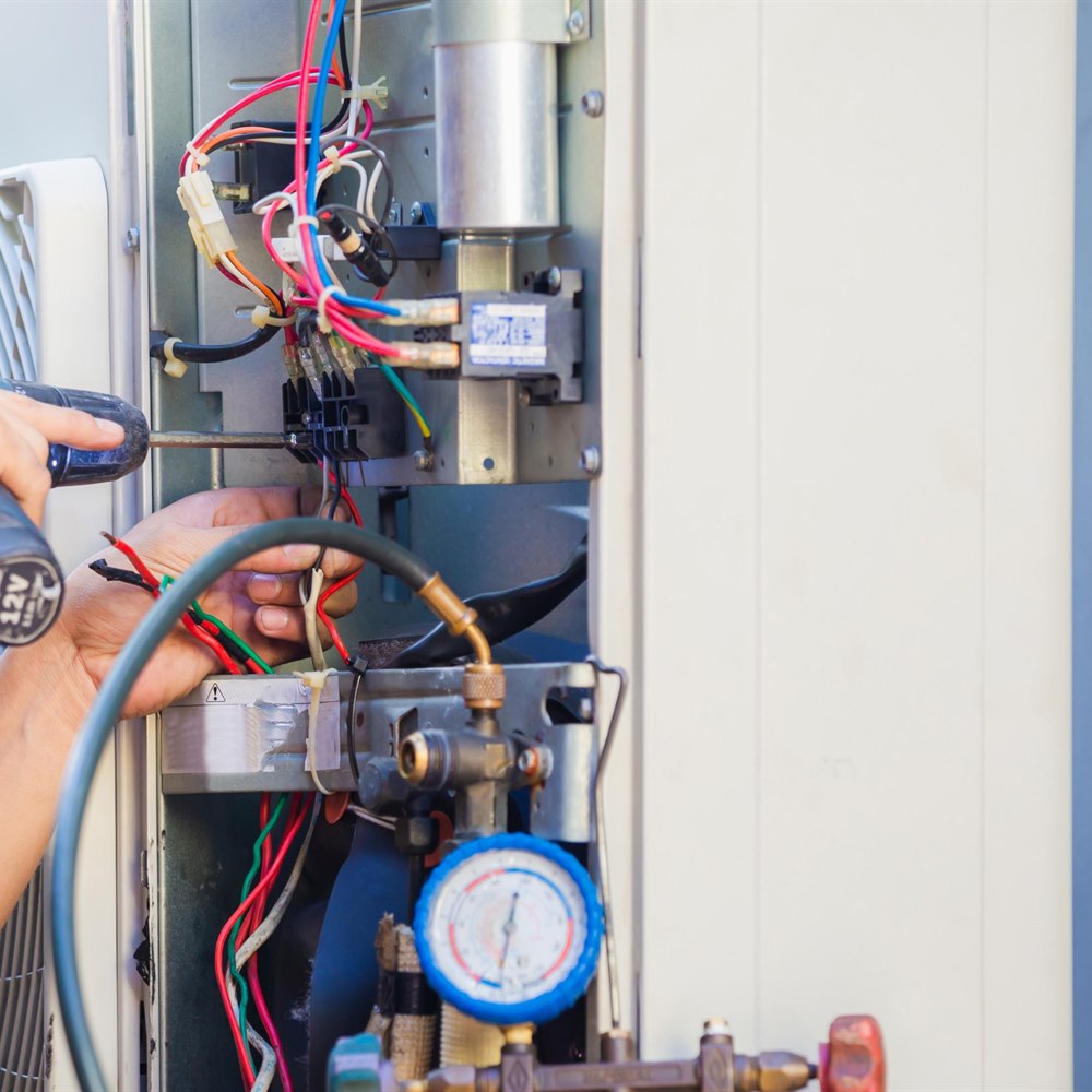 technician-repairing-air-conditioner-with-screwdri Technician repairing air conditioner with screwdriver