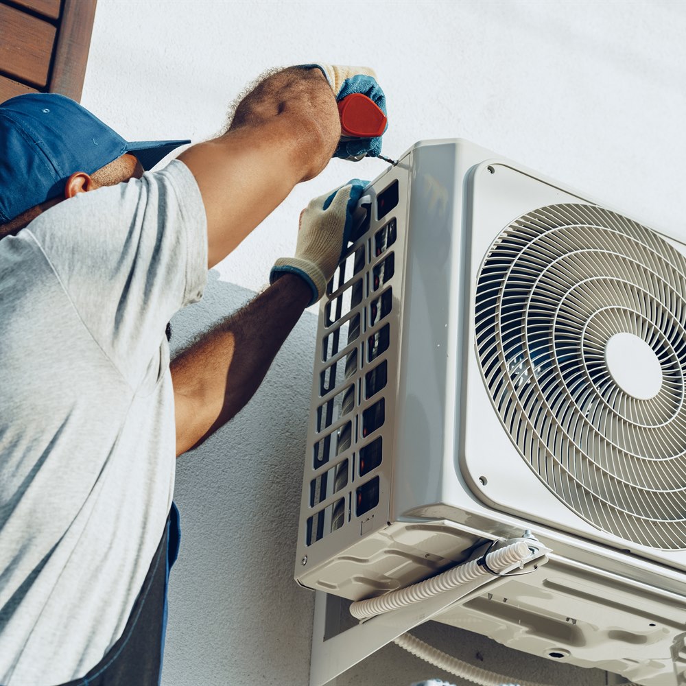 technician-repairing-air-conditioning-unit-on-buil Technician repairing air conditioning unit on building