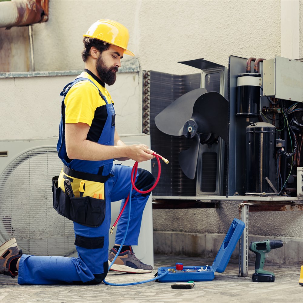 technician-repairs-air-conditioner-unit-outdoors Technician repairs air conditioner unit outdoors