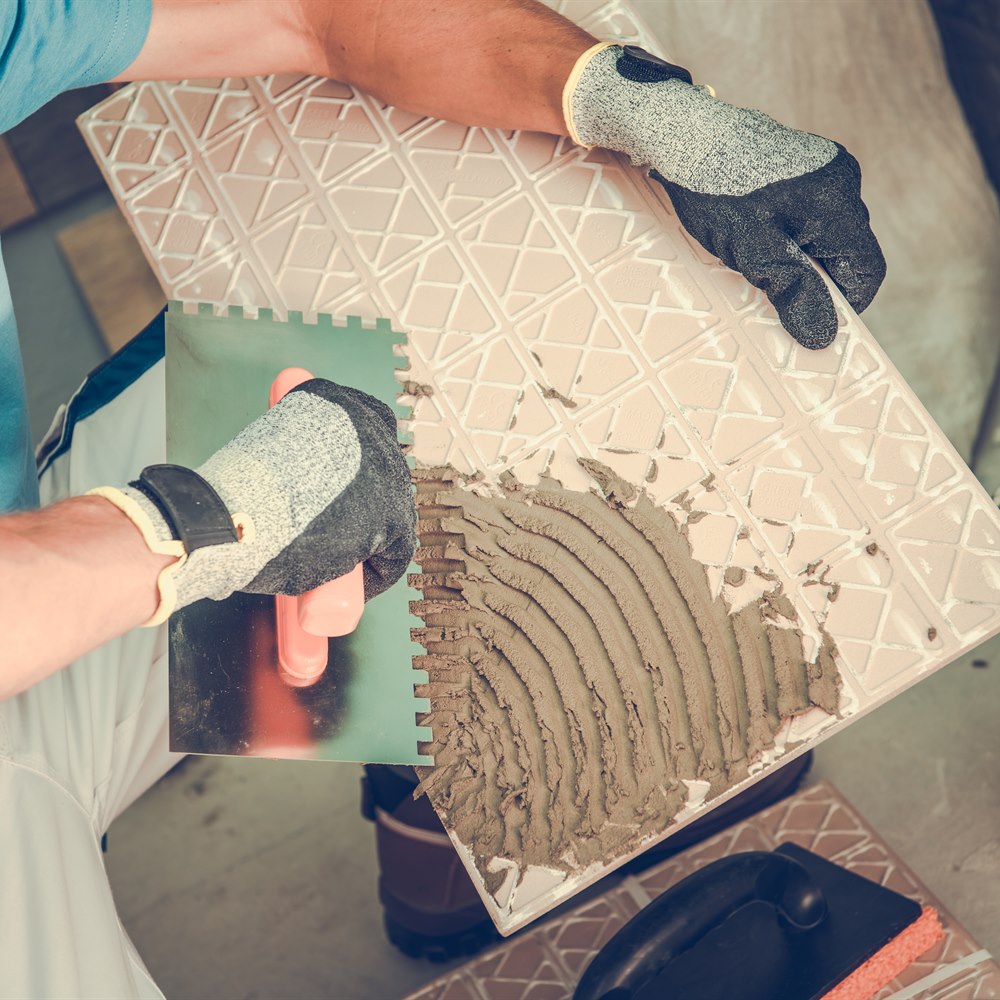 tile-installer-applying-mortar-to-decorative-tile Tile installer applying mortar to decorative tile