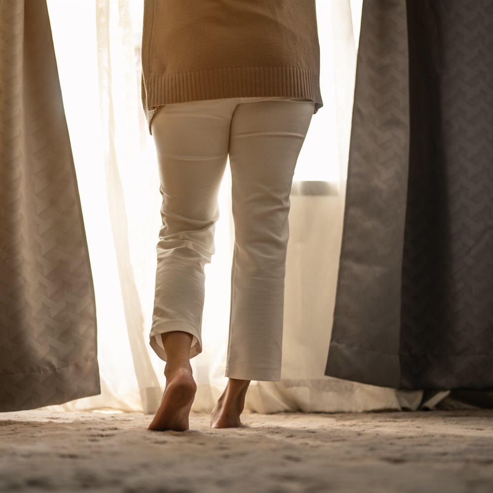 woman-standing-by-window-with-bare-feet Woman standing by window with bare feet