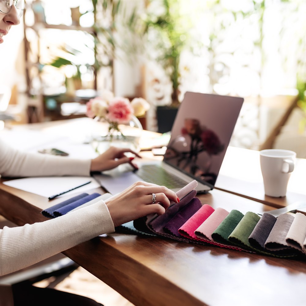 Woman using laptop choosing fabric at desk